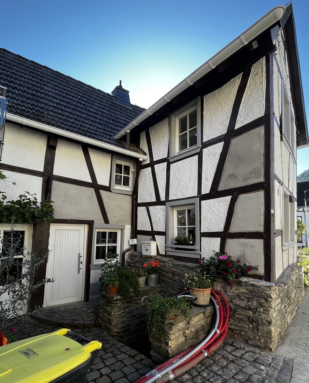 Saniertes Fachwerkhaus Ahrtal Gesamtansicht: helle Fassade, kleiner Eingang, Bepflanzung