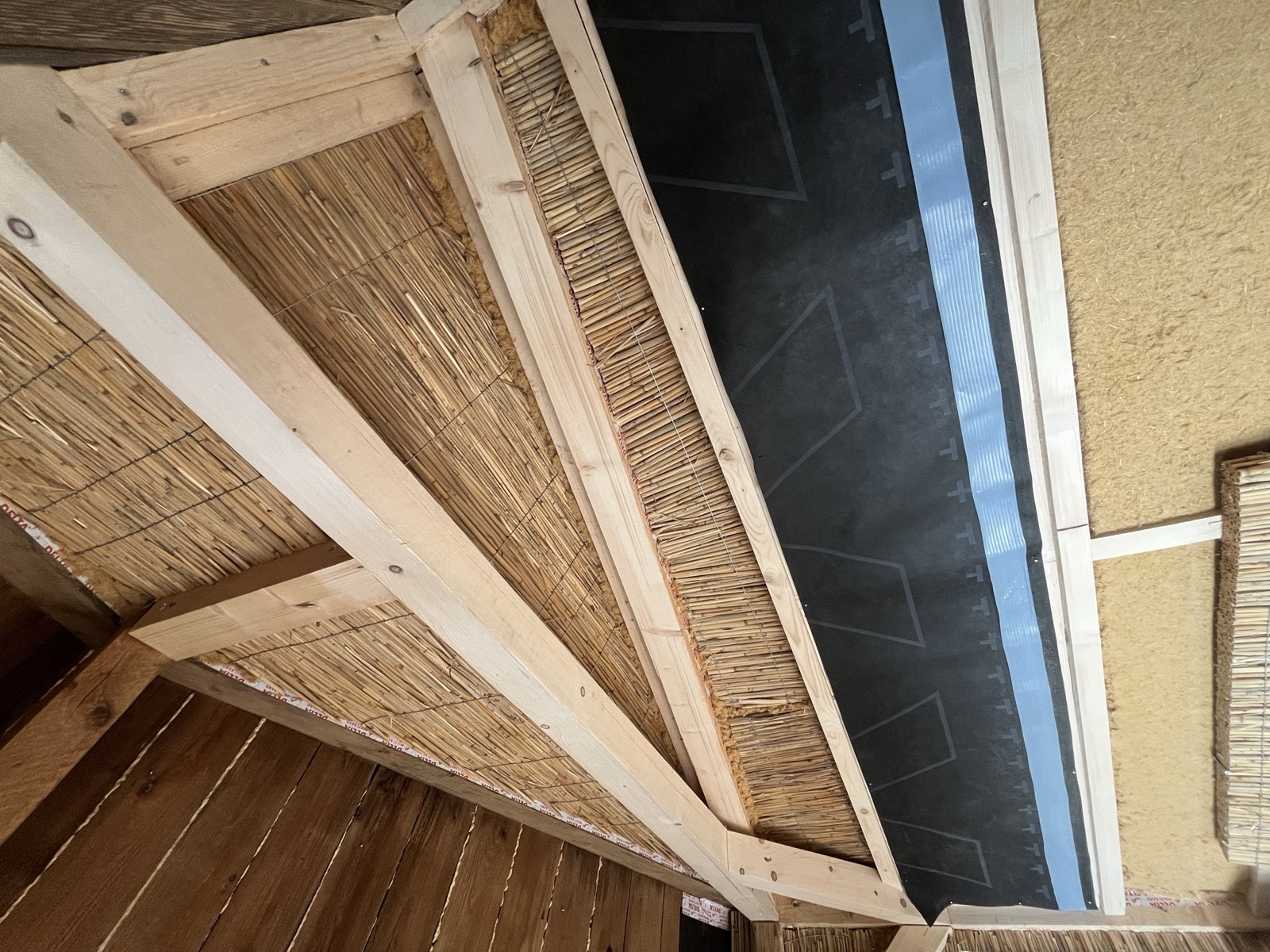 Gartenhaus: Lehmputz auf Schilfrohrwand aufgetragen, warmer Erdton, Putzauftrag